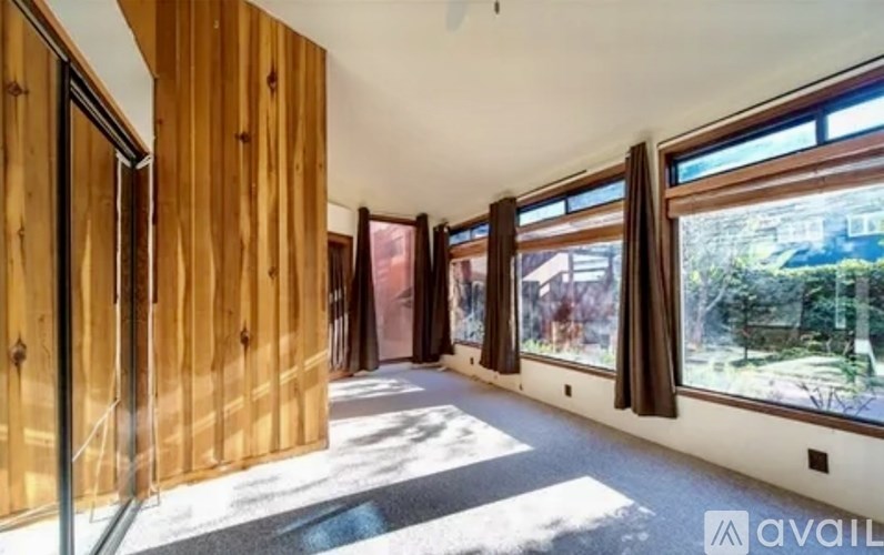 A room with wooden walls and a large window showing an outdoor view.