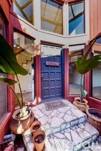 A blue door is in a room with a lot of windows.