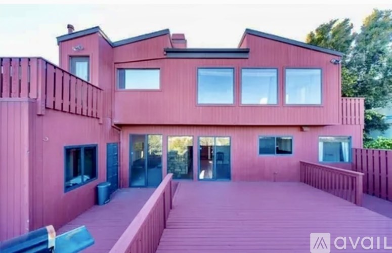 A modern house with a red exterior and a wooden deck.