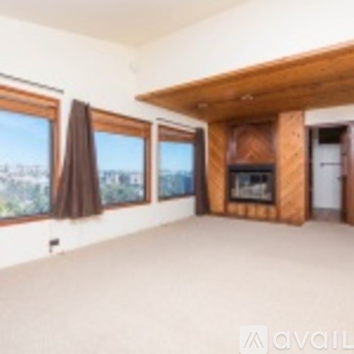 A large empty room with a fireplace and a view of the city.