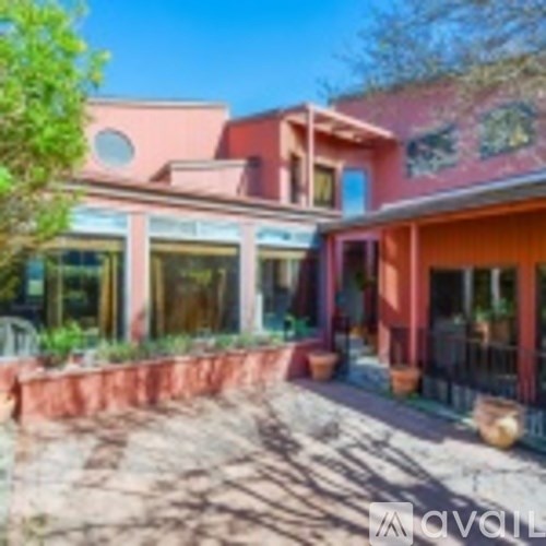 A building with a red and pink facade and a tree in front.
