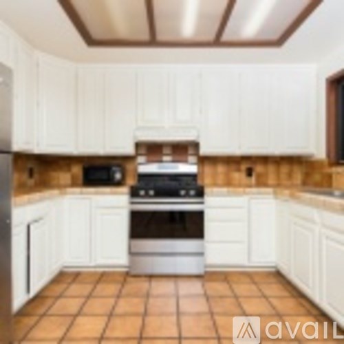 A kitchen with white cabinets and a tile floor.