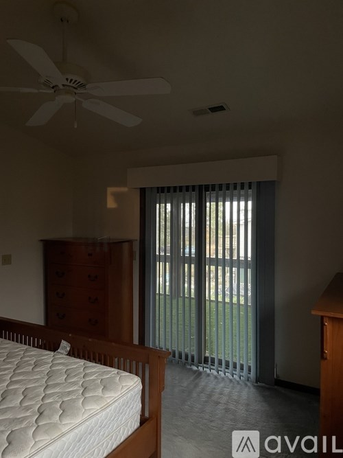A bedroom with a bed, dresser, and window with blinds.