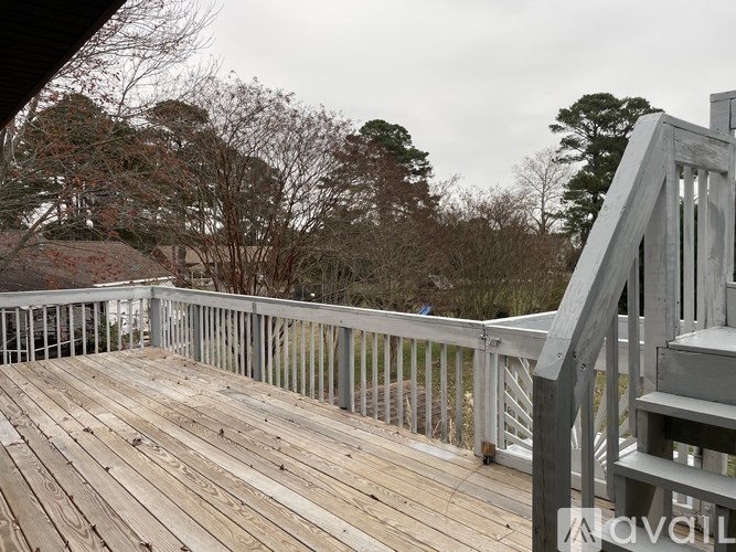 A wooden deck with a railing and a bench overlooking a wooded area.