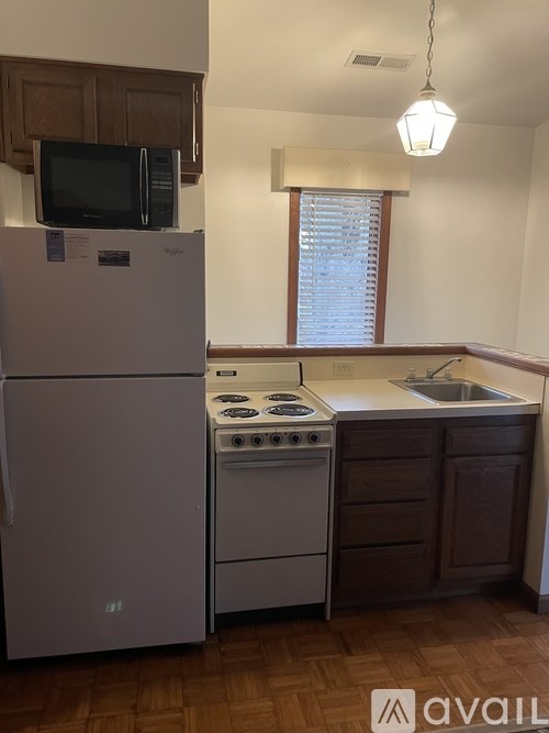 A kitchen with a white fridge, white stove, and a microwave above the fridge.