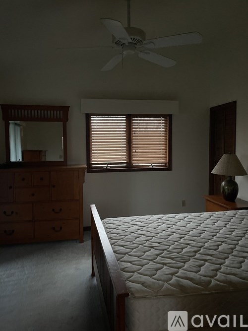 A bedroom with a bed, dresser, and window with blinds.