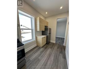 A kitchen with a stove top oven and a refrigerator with a cabinet above it.