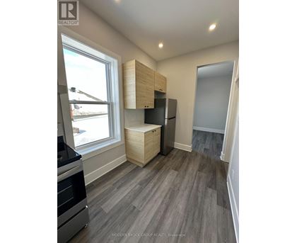 A kitchen with a stove top oven and a refrigerator with a cabinet above it.