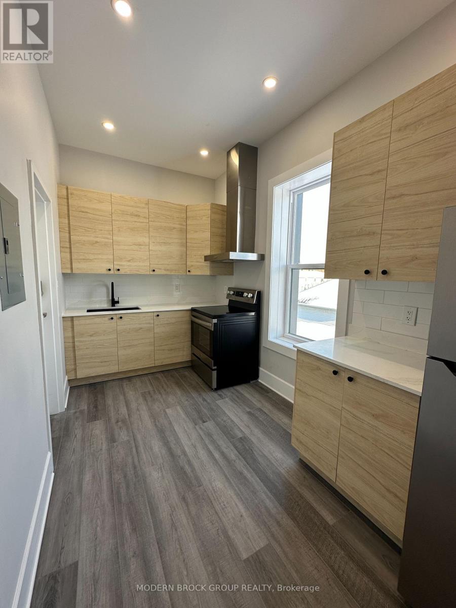 A modern kitchen with wooden cabinets and a grey floor.
