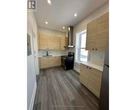 A modern kitchen with wooden cabinets and a grey floor.