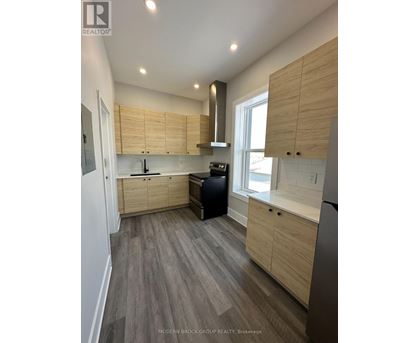 A modern kitchen with wooden cabinets and a grey floor.
