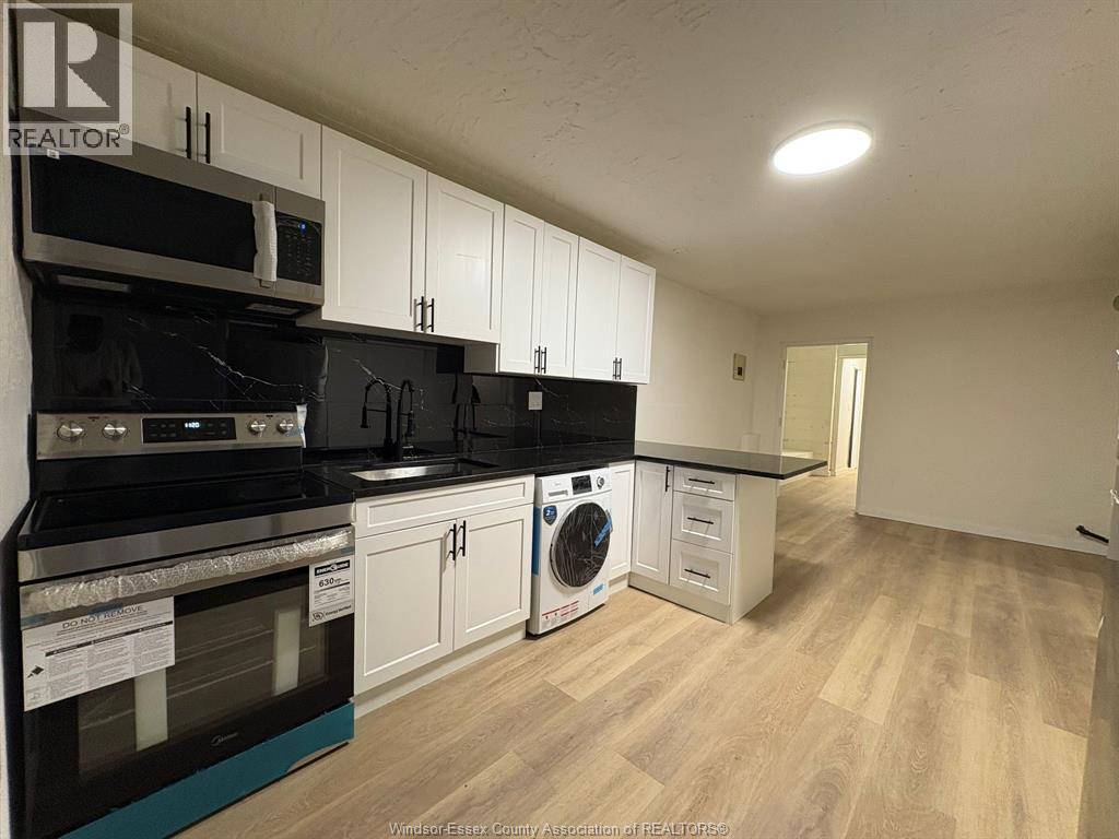 A kitchen with black appliances and white cabinets.
