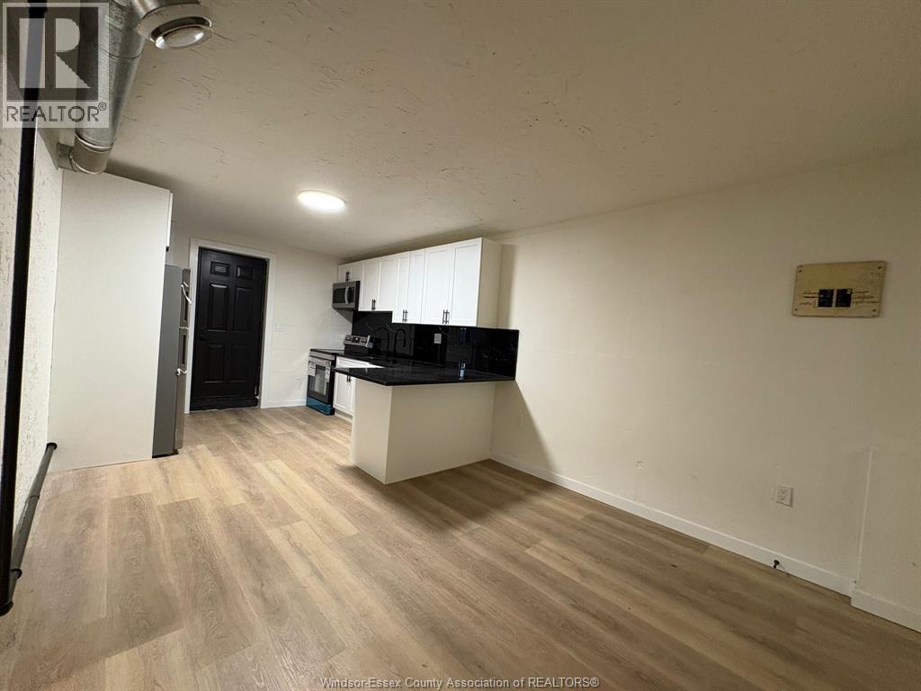 A kitchen area with a black fridge and a white countertop.