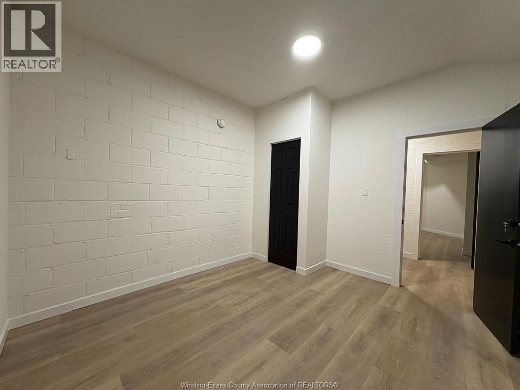 A room with a white brick wall and wooden flooring.