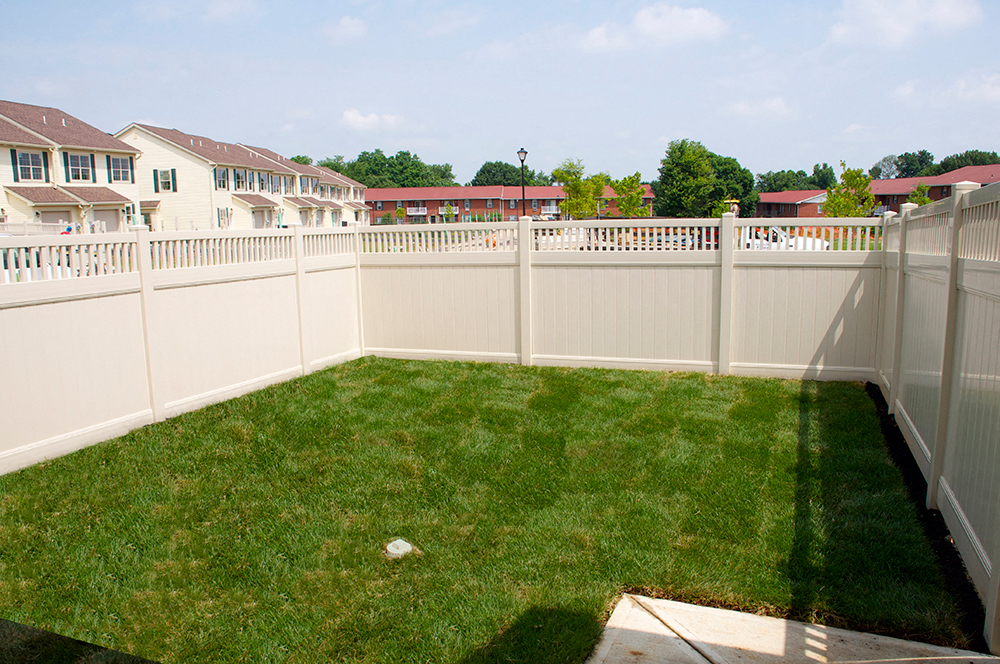 a white fence in a backyard with a green lawn