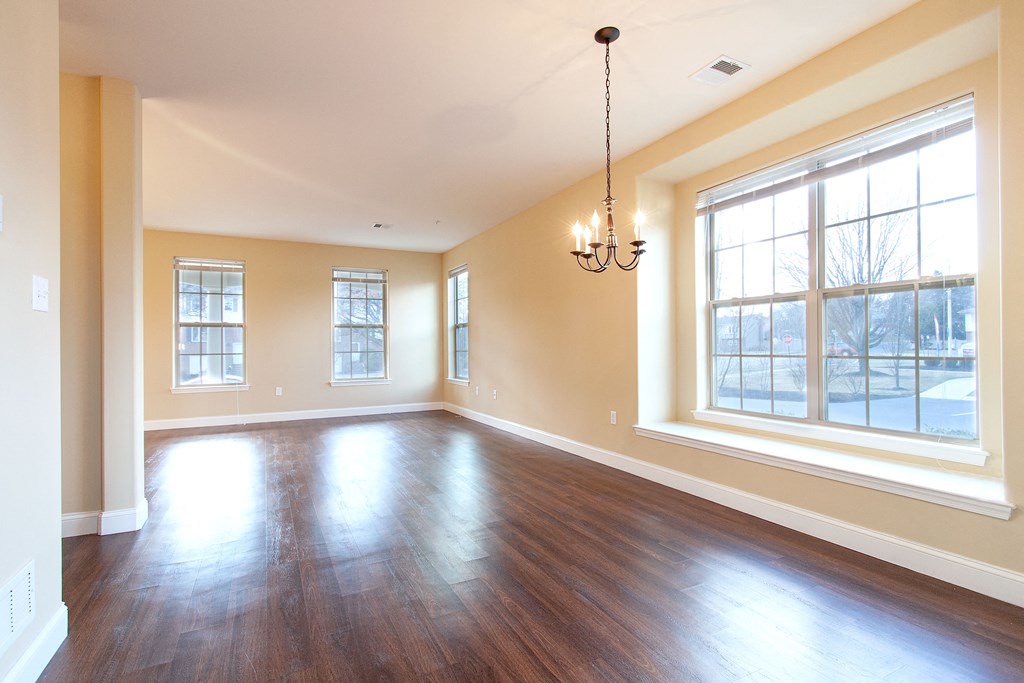 an empty living room with wood floors and a large window