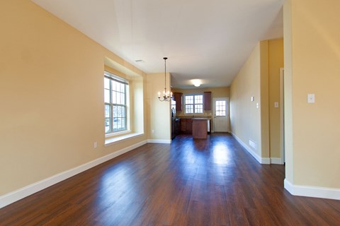 an empty living room with wood floors and a kitchen