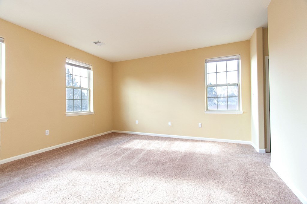 an empty living room with carpet and two windows