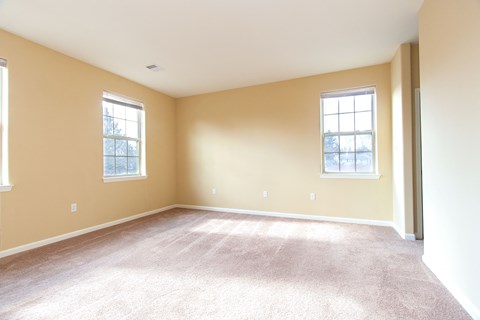 an empty living room with carpet and two windows