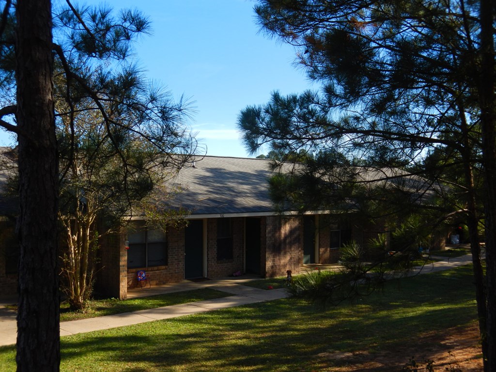 A building with a brown brick facade is surrounded by trees.