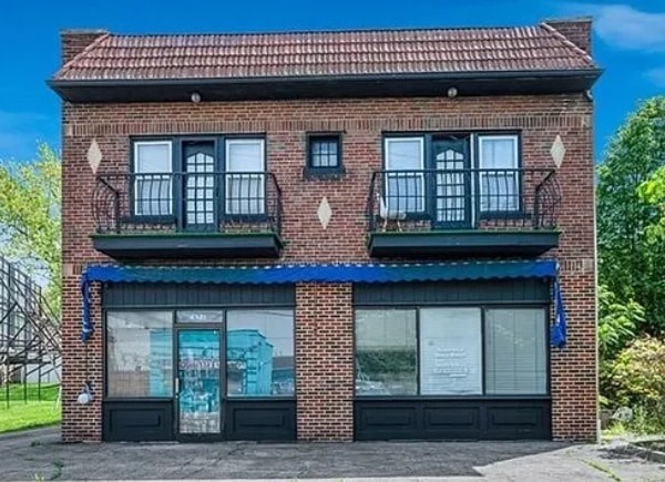 A red brick building with a blue awning and windows with black frames.