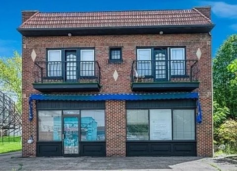 A red brick building with a blue awning and windows with black frames.