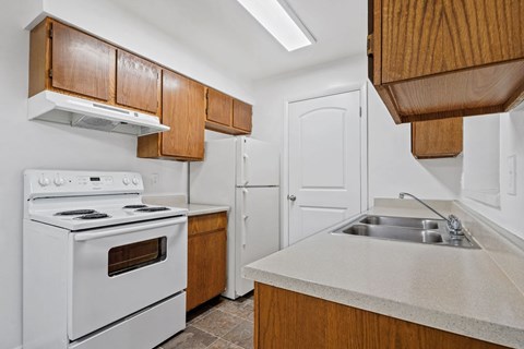 A kitchen with white appliances and wooden cabinets.