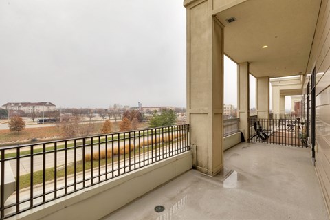 A balcony with a black railing and a concrete floor.