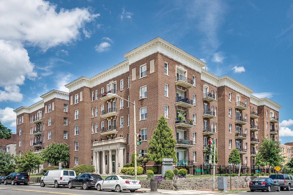 A large red brick building with a white entrance and balconies.