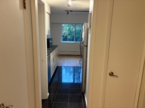 A kitchen with white cabinets and a black floor.