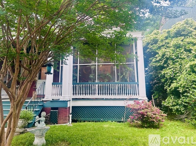 A white house with a balcony and a fountain in front.