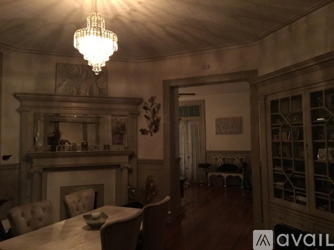 A chandelier hangs from the ceiling in a room with a fireplace and a dining table.