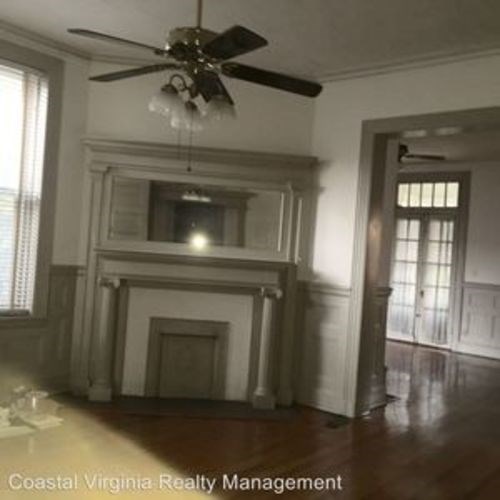 A living room with a fireplace and a ceiling fan.