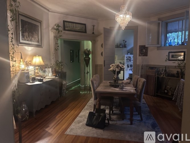 A dining room with a table set for two and a chandelier hanging from the ceiling.