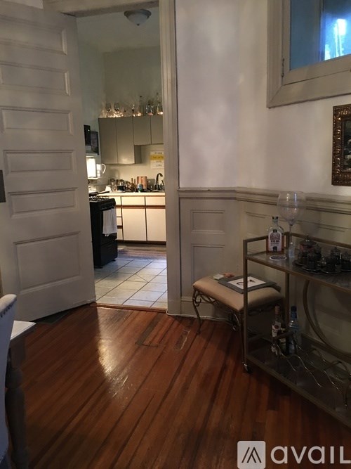 A kitchen with a white door and a wooden floor.