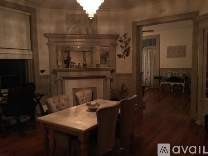 A dining room with a table set for two and a chandelier hanging from the ceiling.