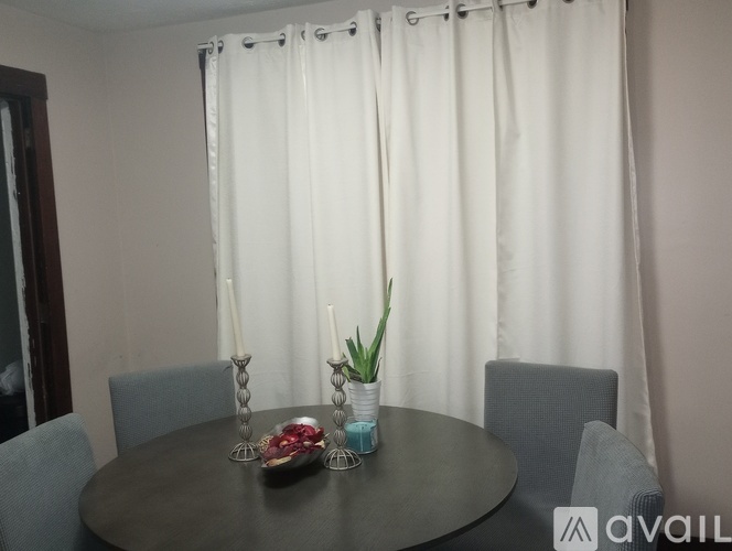 A dining table with chairs and a vase with a plant on it.