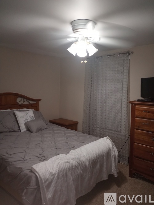 A bedroom with a bed, nightstand, and a dresser with a television on top.