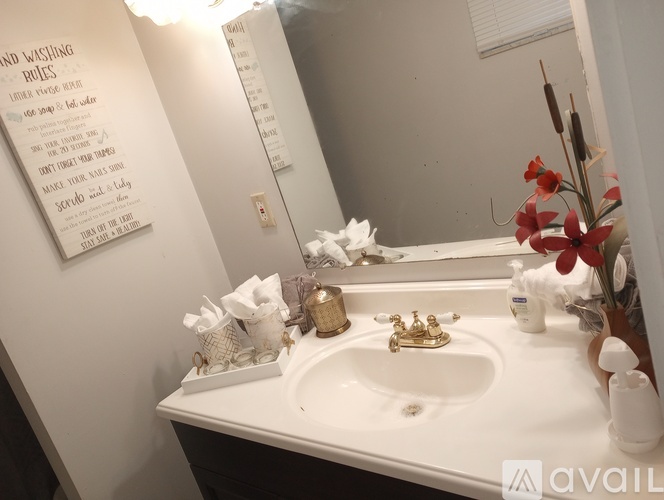A bathroom sink with a mirror above it and a sign on the wall.