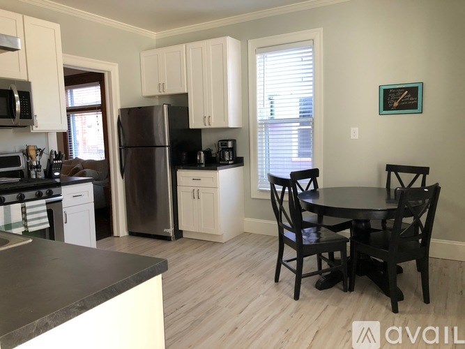 A kitchen with a black countertop and a dining table with four chairs.
