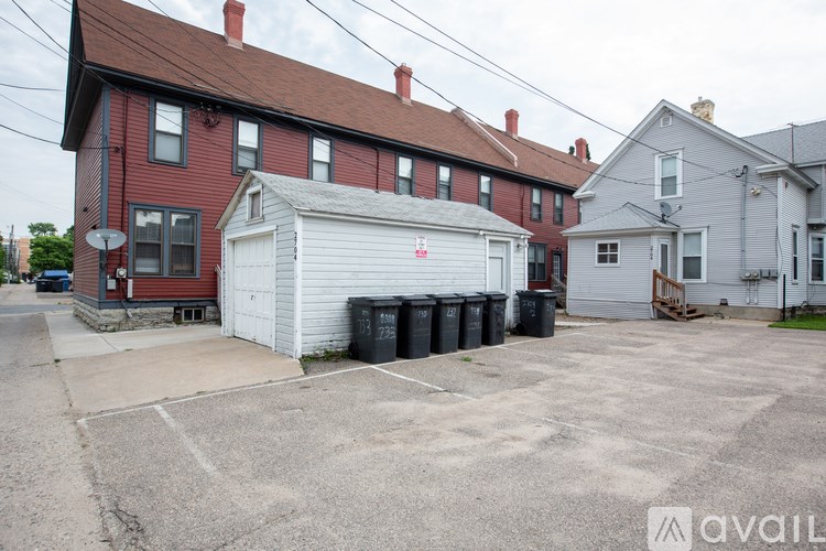 A red brick house with a white garage door and a grey house in the background.