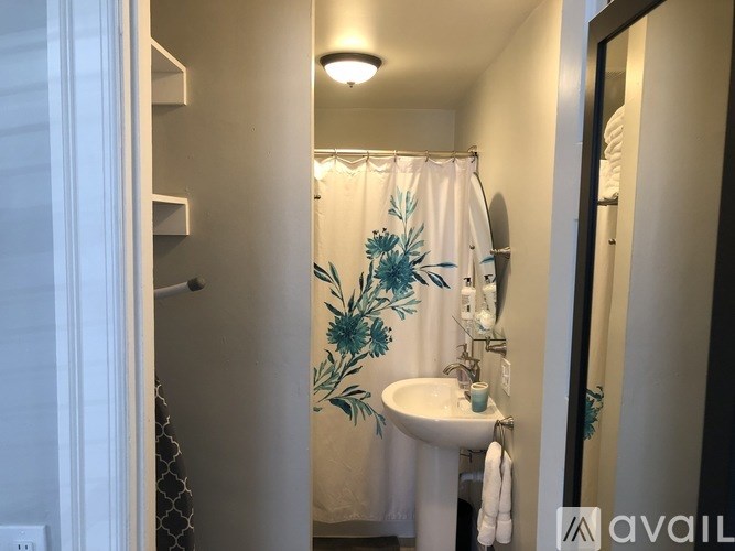 A small bathroom with a sink and a shower curtain with a floral design.