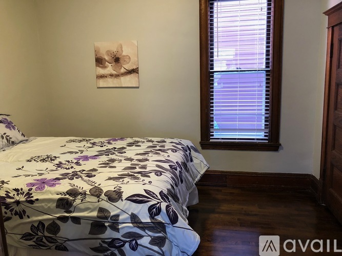 A bedroom with a floral bedspread and a framed picture on the wall.