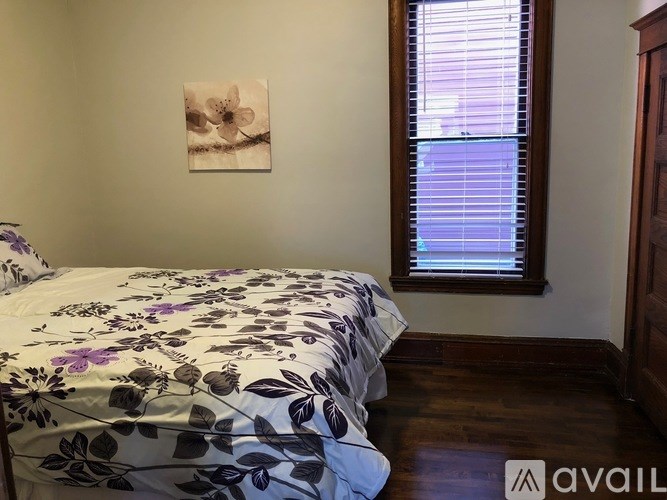 A bedroom with a floral bedspread and a framed picture on the wall.