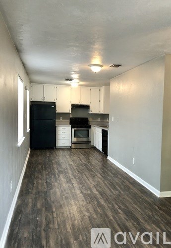 A kitchen with black appliances and wooden floors.