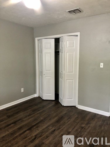 A room with a white door and wooden flooring.