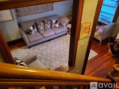 A living room with a grey couch and a patterned rug.