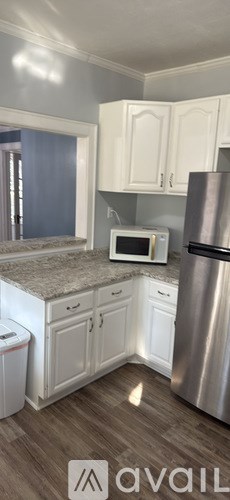 A kitchen with white appliances and wooden floors.