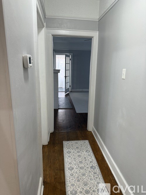 A hallway with a door at the end and a mat on the floor.