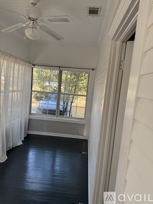 A room with a ceiling fan and a window with a view of the outside.